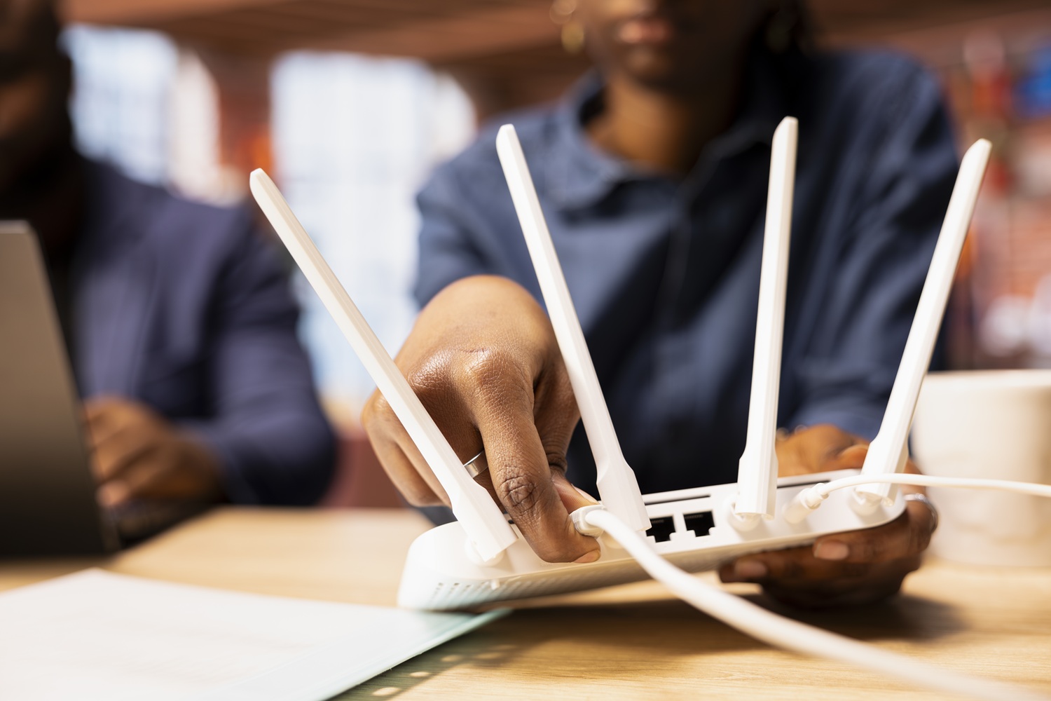Black woman and man rebooting the WI FI router by moving the cables, troubleshooting to restore the internet connection. Freelancers at home struggling with signal loss or lag.